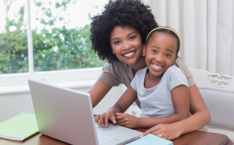 Happy mother and daughter using the laptop at home