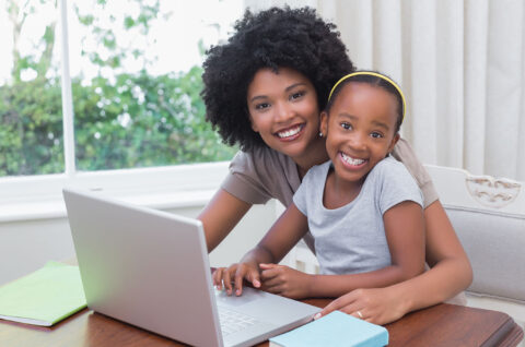 Happy mother and daughter using the laptop at home